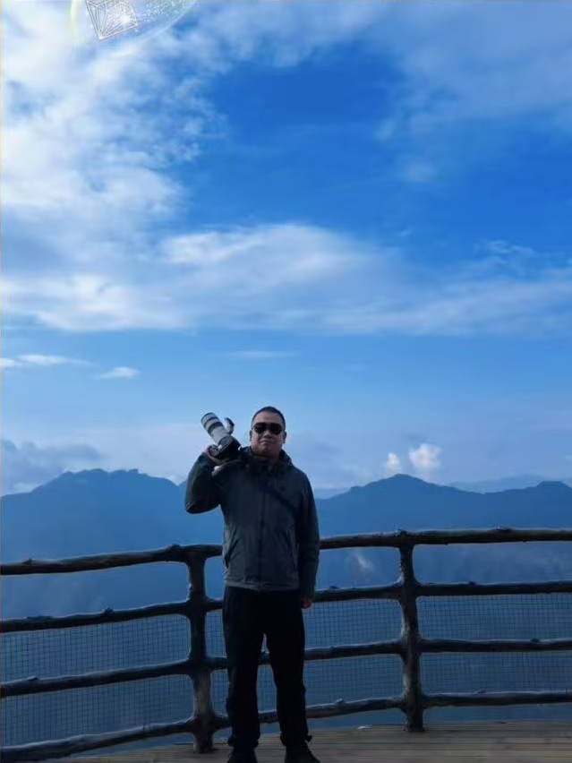 臭宝牛带着相机站在山间观景台上